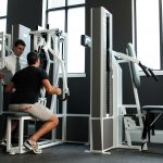 Chiropractor guiding male through exercise on machine