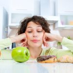 Woman thinks "what should I eat?" as she looks at healthy and unhealthy food